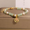 Green bamboo jade bracelet with pearls and a pink flower charm on a box