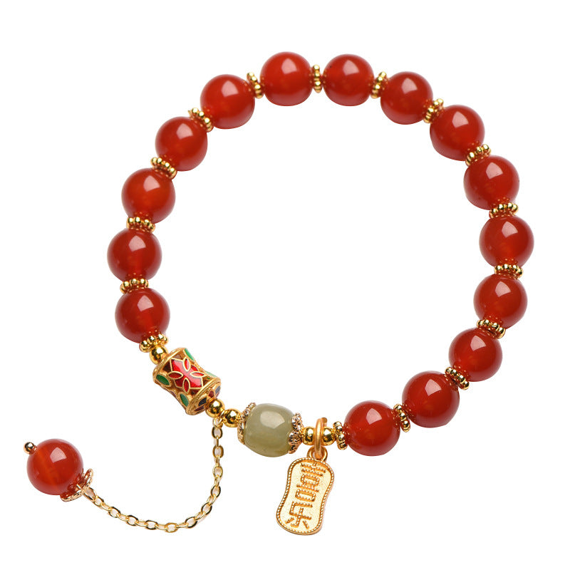 Red beaded bracelet with gold-tone spacers and a hanging charm on a white background