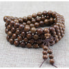 Close-up of a brown wooden 108 bead mala bracelet coiled on a textured surface