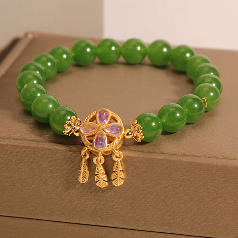 Green crystal bead bracelet with gold tone four leaf clover and dreamcatcher charm
