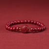 Red cinnabar beaded bracelet with a carved zodiac charm held in a hand