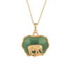 Gold tone elephant pendant necklace with green jade-like stone on wooden surface