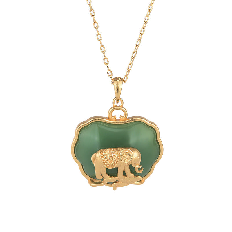 Gold tone elephant pendant necklace with green jade-like stone on wooden surface