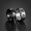Black and silver stainless steel rings with rotating Yin Yang symbols on a dark background