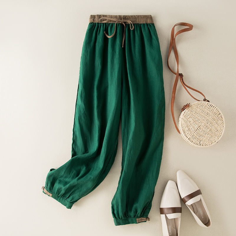 Green cotton linen harem pants with elastic waist laid flat next to accessories