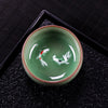 Top down view of a green celadon teacup with two white koi fish painted inside