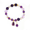 Close-up of a purple beaded bracelet with a gold flower pendant on a white background