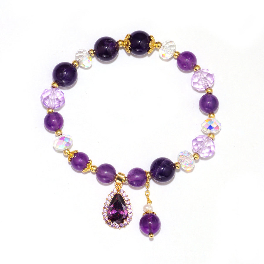 Close-up of a purple beaded bracelet with a gold flower pendant on a white background