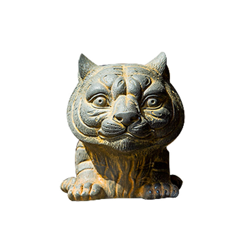 Small resin tiger statue with a rustic finish sitting on a wooden surface