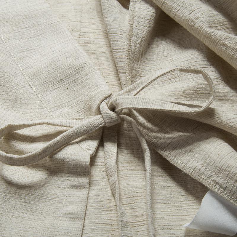 Close-up detail of the tie closure on a beige men's cotton linen jacket.