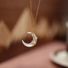 Crescent moon pendant made of white mother of pearl shell hanging on a gold-tone chain