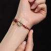 Woven red cord bracelet with jade donut and gold koi fish charm on wrist
