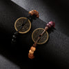 Two handmade wood bracelets with coin charms resting on a dark surface