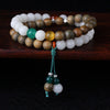 Multi-wrap bracelet with green wood and white bodhi seed beads on a dark surface