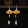 Pair of handmade yellow ginkgo leaf earrings with white flower charms and pale drop beads